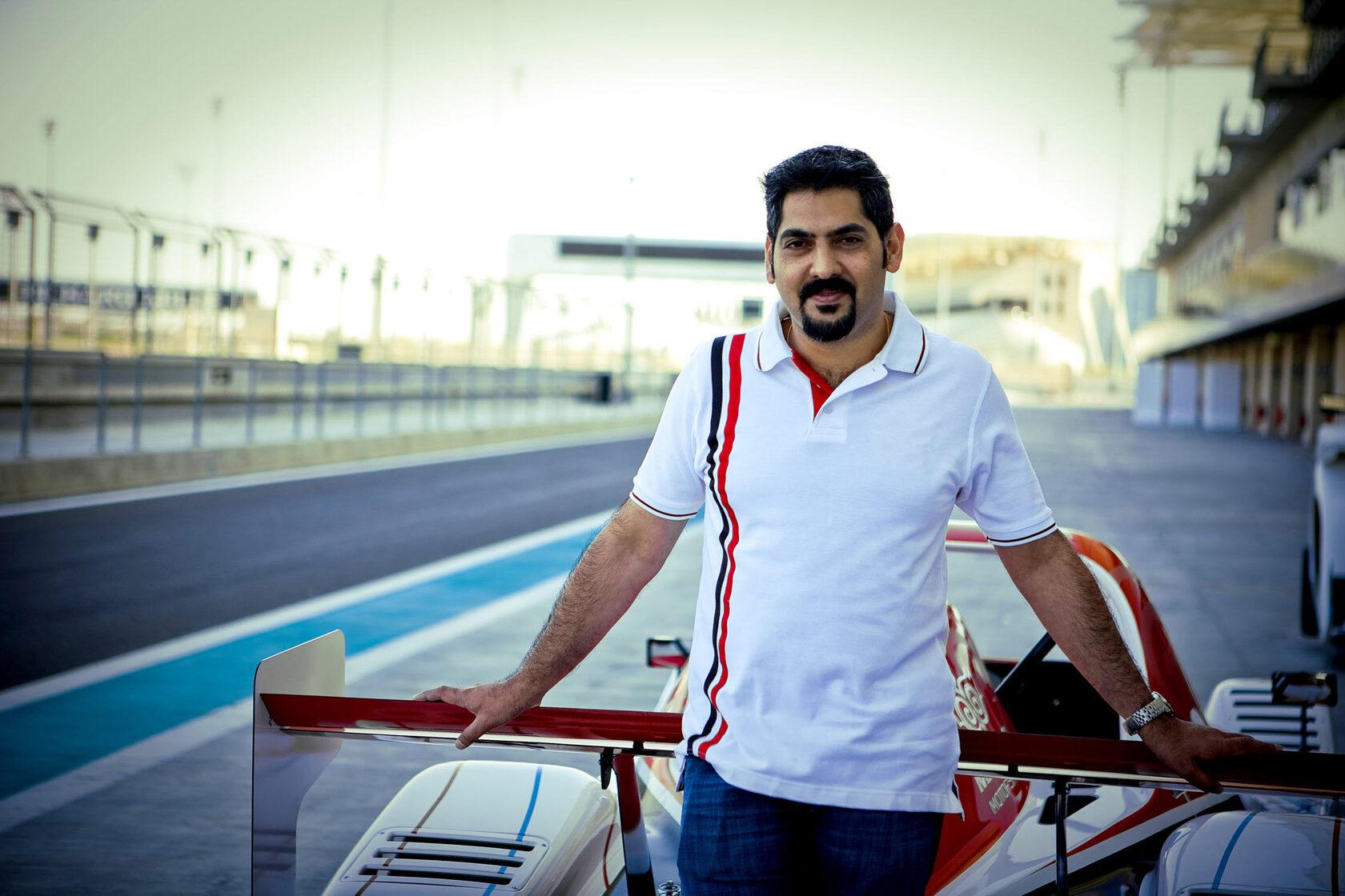 Darshan M leaning into the cockpit of a race car on a racetrack