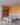 An interior render of a modern loft bedroom featuring a striking orange accent wall and built-in bookshelf. This 3D visualization details a grey bed, herringbone wood floors, a concrete ceiling, and stylish spiral pendant lights. Link to project details.