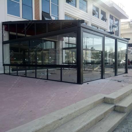 Wall-mounted retractable pergola with guillotine and frameless glazing