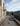 Villa under construction in Bordighera, Liguria, with stone walls, wooden balcony railings, construction scaffolding, and panoramic views of mountainous landscape below.