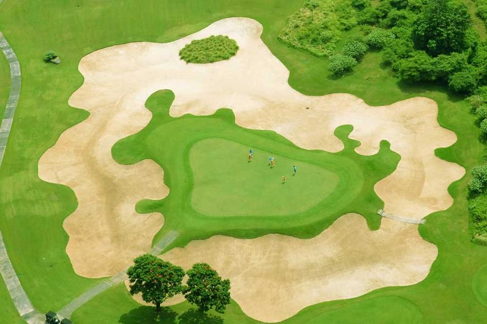 Aerial view of a New Kuta Golf green surrounded by a large sand bunker