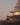 A detailed 3D render of a futuristic building's terrace at sunset, featuring a person looking out over the landscape from a curved concrete walkway.