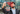 Man taking a selfie with his phone for face verification, smiling against an urban street backdrop.