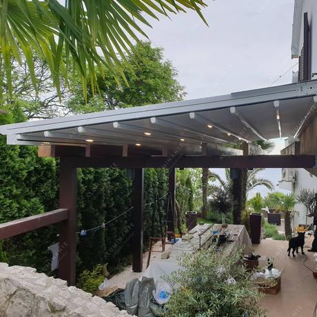 Wall-mounted retractable pergola canopy by a house
