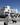 An exterior visualization of modern white minimalist townhouses on a sunny day. This photorealistic visualization features a man walking a dog in the foreground and a woman with a stroller on the sidewalk. Link to project details.
