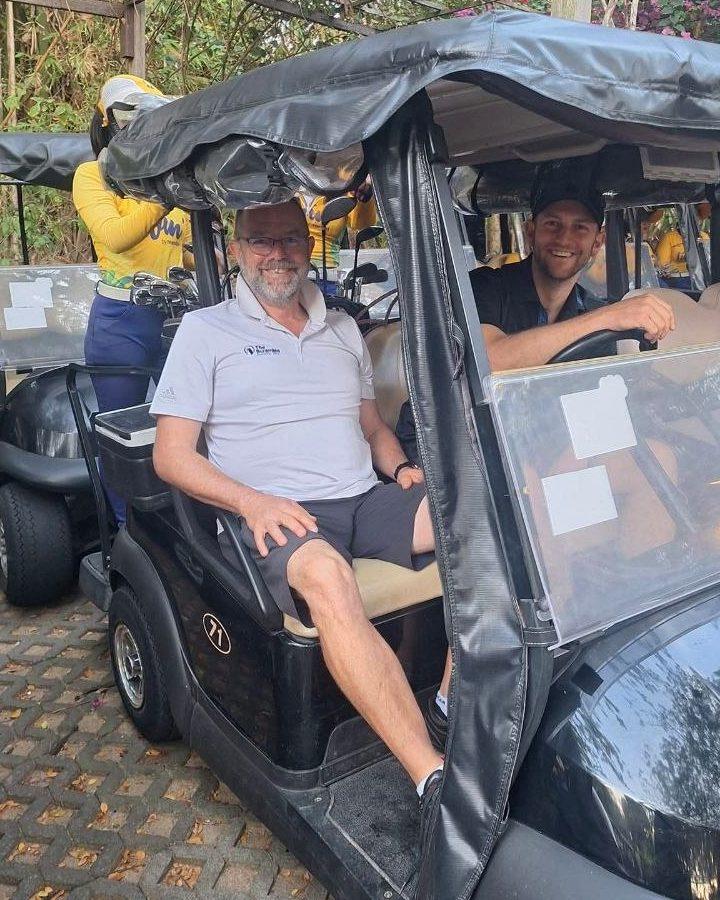 Two smiling golfers in a golf cart before the round