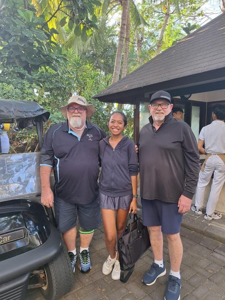 Two golfers with a member of the club team at the clubhouse