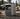 Portable power station placed on gravel at an outdoor campsite with forest, truck, and tent in the background