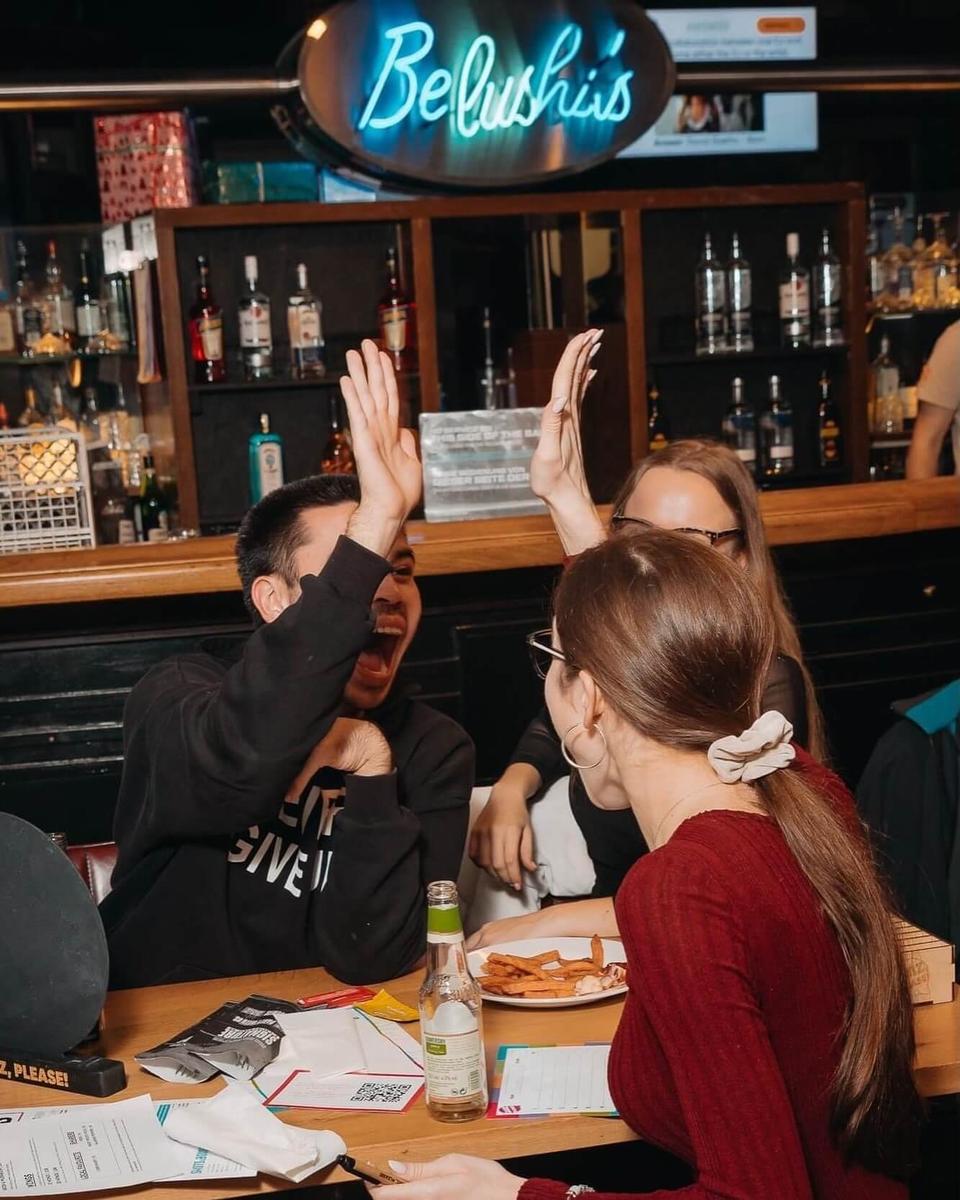 Teammates high-fiving at the table after a correct answer