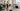 A bright, modern lifestyle photo of a diverse young professional team working together in a stylish Barcelona office with large windows and city views. Warm Mediterranean light, relaxed but focused atmosphere. Mix of laptop work, conversation, and collaboration. Aesthetic: clean, editorial, optimistic